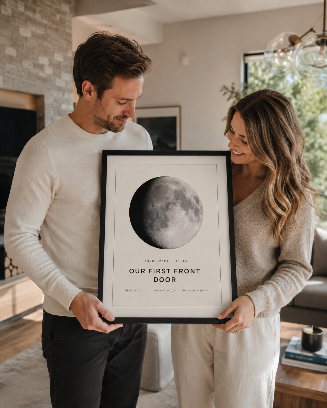 Couple holding a framed moon phase print in their living room